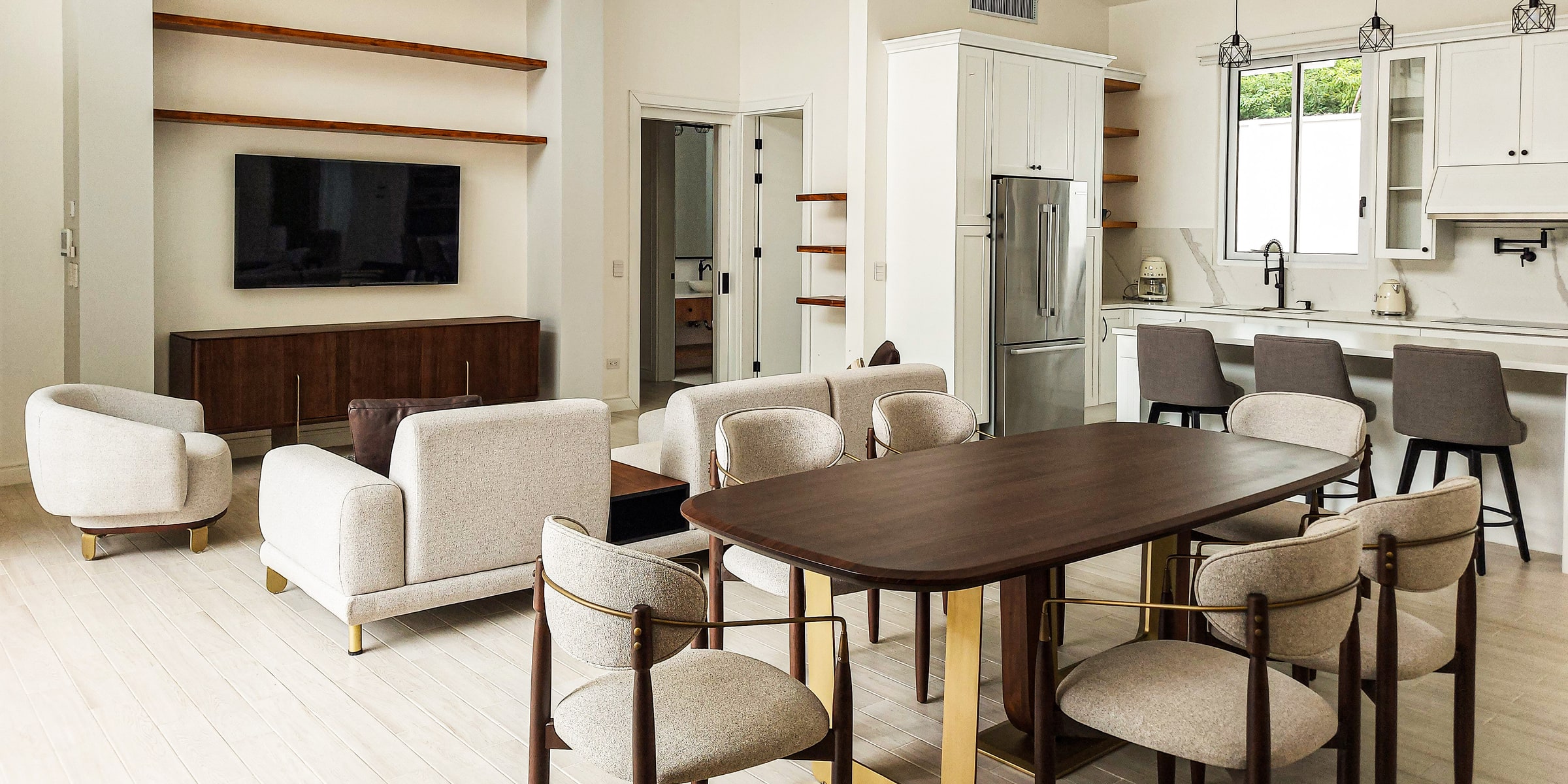 Bright open kitchen and dining room with walnut table and cream upholstered chairs
