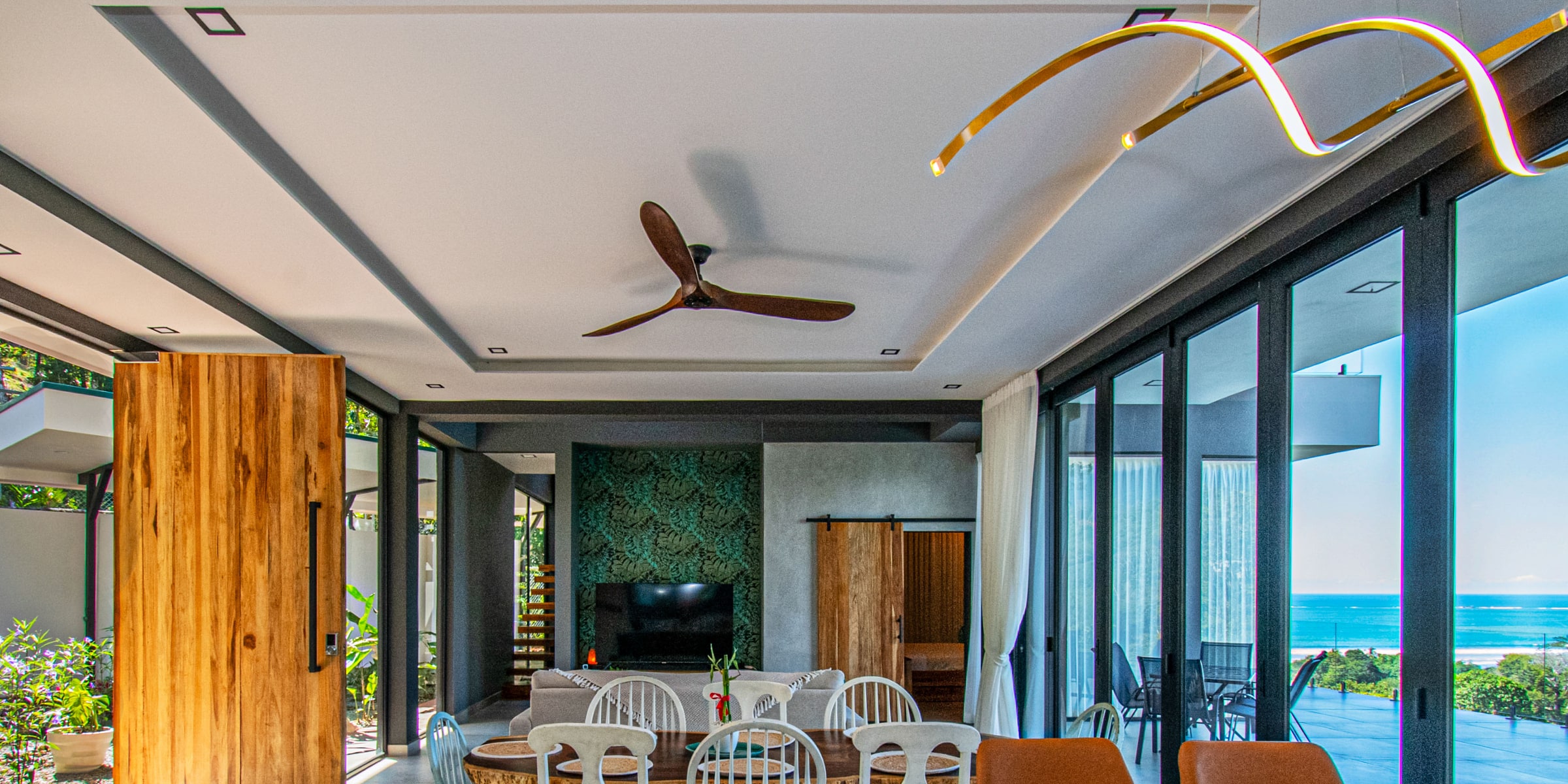 Villa Unique open living and dining room with a sculptural brass light and an ocean view