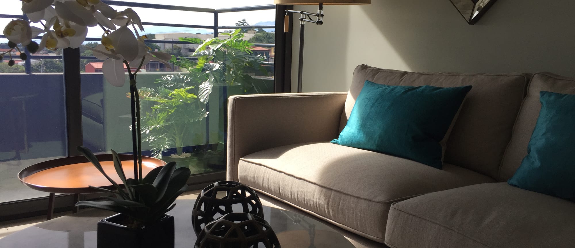 Nueve84 living room with a grey sofa, teal cushions and a balcony view